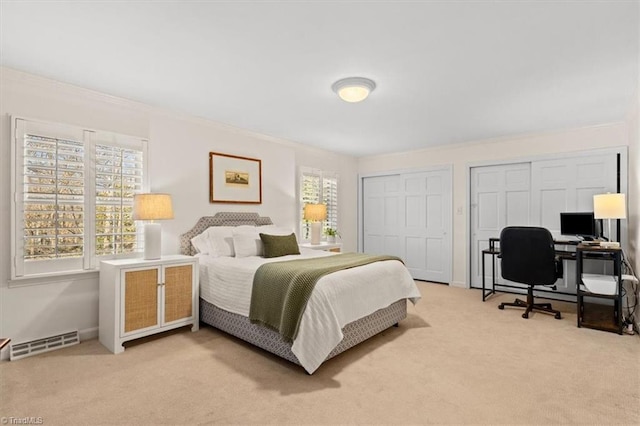 bedroom with light carpet, two closets, and crown molding