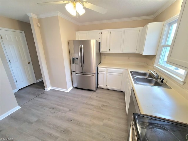 kitchen with a sink, white cabinetry, light countertops, stainless steel fridge, and crown molding