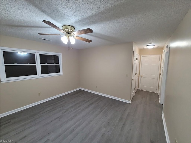 empty room featuring visible vents, a textured ceiling, baseboards, and wood finished floors