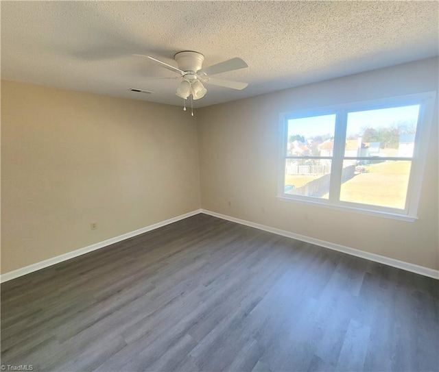 spare room with visible vents, dark wood-type flooring, ceiling fan, a textured ceiling, and baseboards