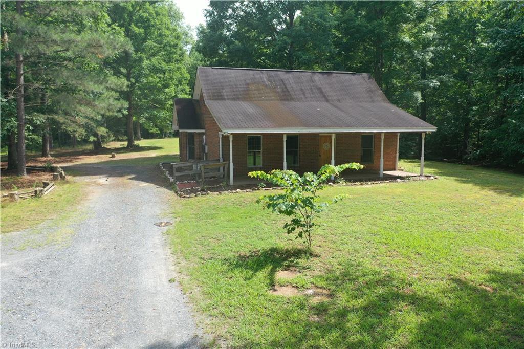 5864 Whites Chapel Rd, Staley, NC 27355 - view of front of home featuring gravel driveway, a porch, a front lawn, and a wooded view