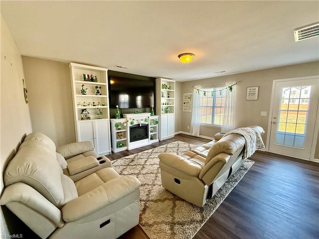 living area with visible vents, wood finished floors, and a tiled fireplace