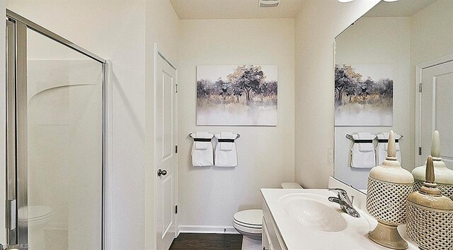 bathroom featuring vanity, toilet, a shower with shower door, and hardwood / wood-style floors