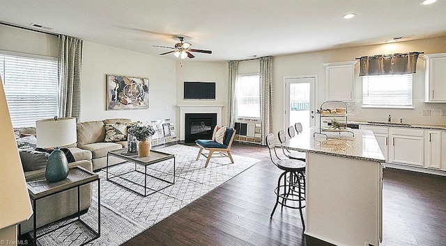 living room featuring ceiling fan, plenty of natural light, dark hardwood / wood-style flooring, and sink