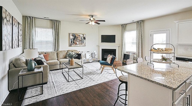 living room featuring dark wood-type flooring and ceiling fan