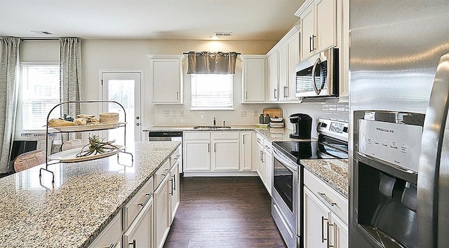 kitchen with sink, light stone counters, appliances with stainless steel finishes, dark hardwood / wood-style flooring, and white cabinets