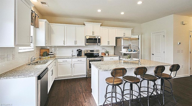 kitchen with appliances with stainless steel finishes, a center island, sink, and white cabinets