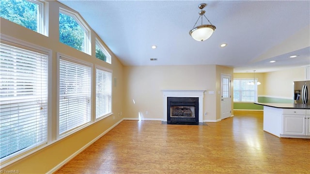 unfurnished living room with light wood-type flooring and high vaulted ceiling