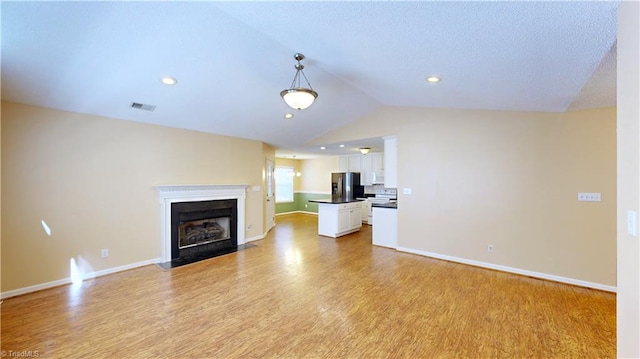 unfurnished living room with light hardwood / wood-style flooring and vaulted ceiling