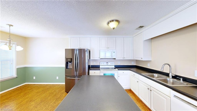 kitchen featuring white appliances, sink, light hardwood / wood-style flooring, a notable chandelier, and white cabinetry