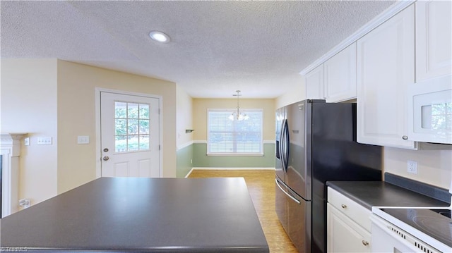 kitchen with range, white cabinets, hanging light fixtures, and an inviting chandelier