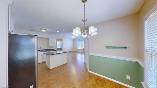 kitchen featuring sink, a chandelier, white cabinets, light hardwood / wood-style floors, and stainless steel refrigerator