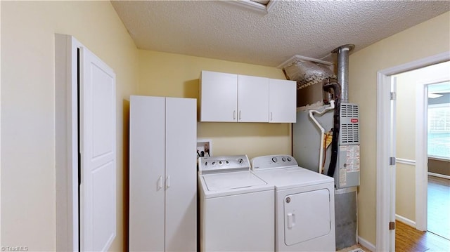 washroom featuring cabinets, independent washer and dryer, a textured ceiling, and light hardwood / wood-style flooring