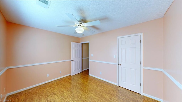 unfurnished bedroom with ceiling fan, a textured ceiling, and light wood-type flooring