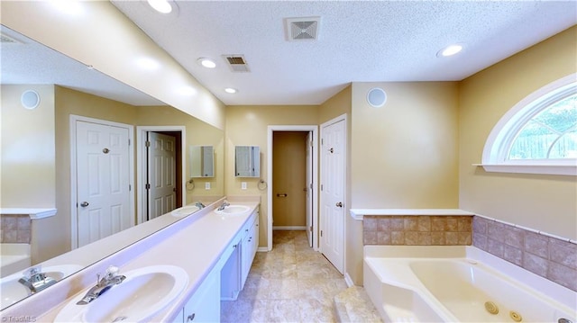 bathroom featuring a bathtub, vanity, and a textured ceiling