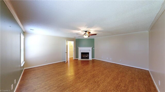 unfurnished living room featuring ceiling fan, wood-type flooring, a textured ceiling, and ornamental molding