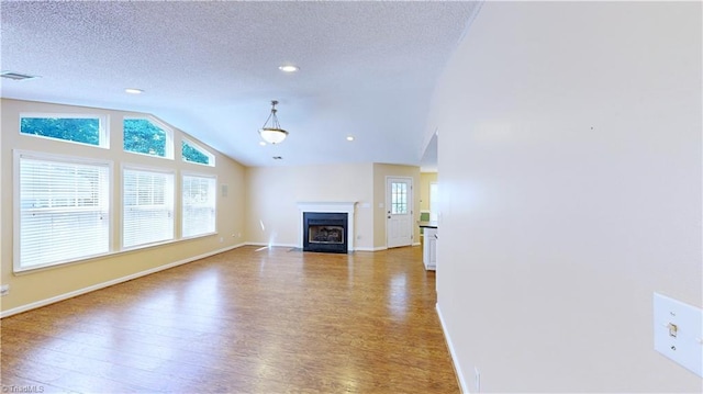 unfurnished living room with a textured ceiling, hardwood / wood-style floors, and vaulted ceiling