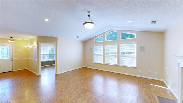 unfurnished living room featuring plenty of natural light, wood-type flooring, and lofted ceiling