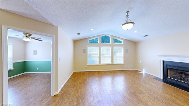 unfurnished living room with hardwood / wood-style floors, ceiling fan, a textured ceiling, and vaulted ceiling