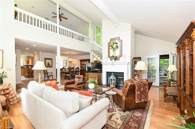 8009 Willow Glen Trl, Greensboro, NC 27455 - living room featuring high vaulted ceiling, ceiling fan, light wood-style flooring, a glass covered fireplace, and healthy amount of natural light