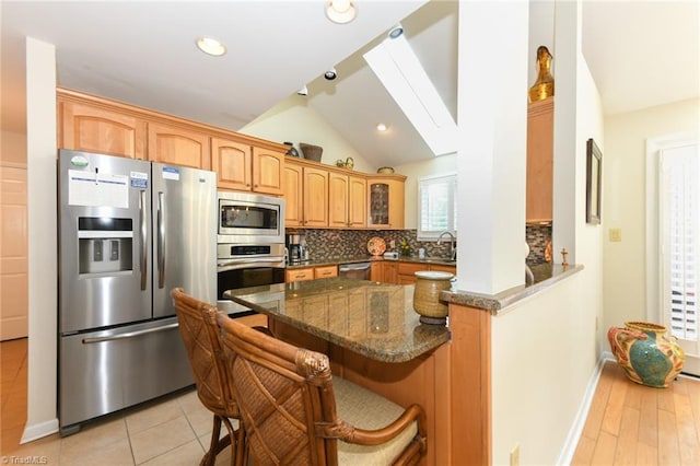 8009 Willow Glen Trl, Greensboro, NC 27455 - kitchen with stainless steel appliances, decorative backsplash, dark stone countertops, vaulted ceiling, and a breakfast bar