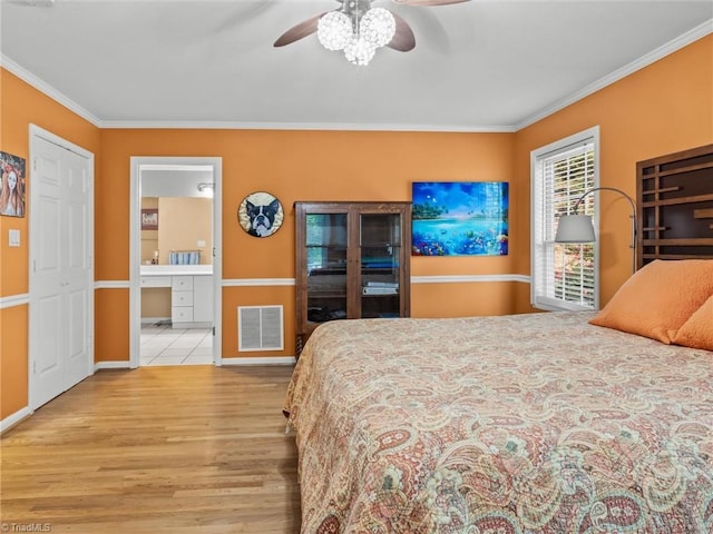 bedroom with light wood-type flooring, ceiling fan, ornamental molding, and ensuite bath