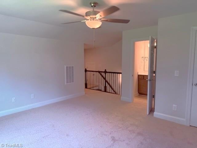 unfurnished room with a ceiling fan, visible vents, light carpet, and baseboards