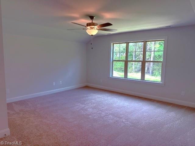 empty room featuring light colored carpet, a ceiling fan, and baseboards