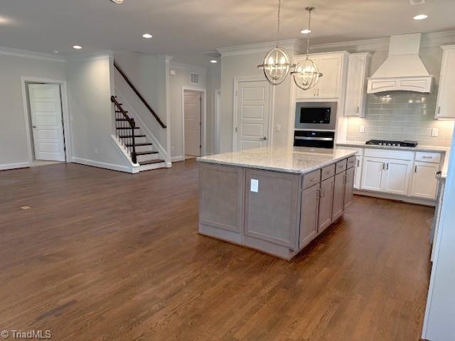 kitchen with ornamental molding, wall oven, custom range hood, and gas cooktop