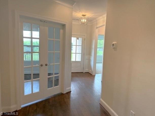 doorway featuring an inviting chandelier, crown molding, baseboards, french doors, and dark wood finished floors
