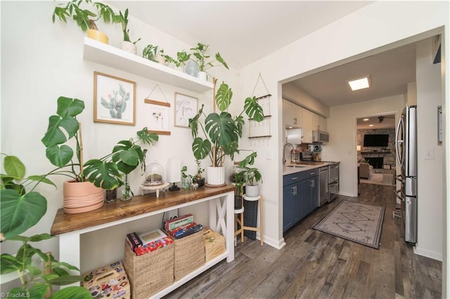 bar featuring freestanding refrigerator, stove, dark wood-type flooring, a sink, and baseboards