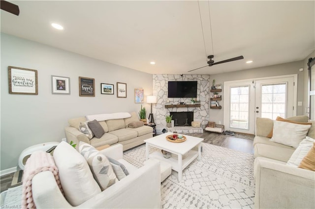 living room featuring ceiling fan, wood finished floors, a stone fireplace, and recessed lighting