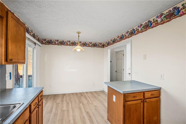 kitchen with pendant lighting, light hardwood / wood-style floors, sink, and a textured ceiling