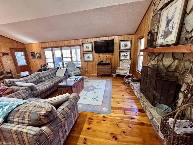 living room with a fireplace, hardwood / wood-style flooring, vaulted ceiling, and wood walls