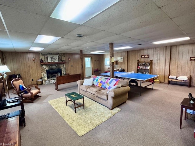 rec room with a paneled ceiling, wooden walls, a fireplace, and carpet floors