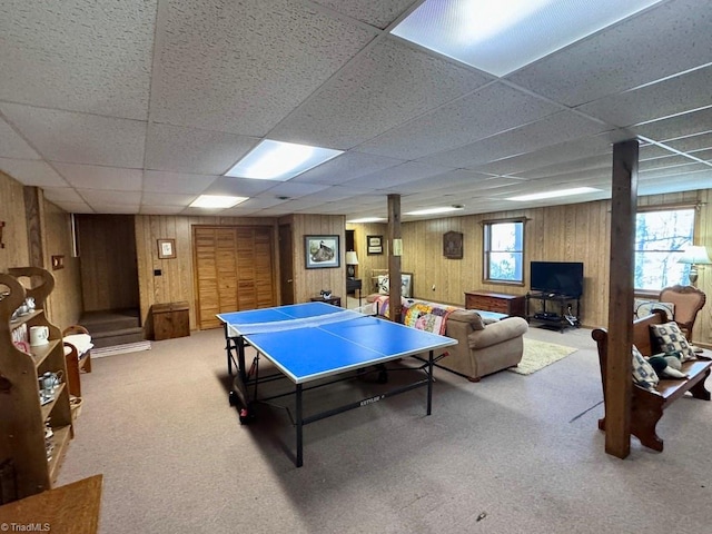 game room with carpet flooring, a drop ceiling, and wood walls