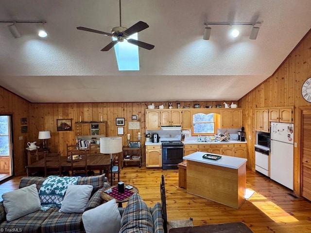 kitchen with track lighting, vaulted ceiling, black appliances, light hardwood / wood-style flooring, and wood walls