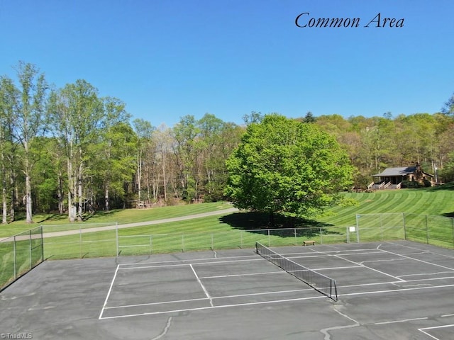 view of tennis court featuring a lawn