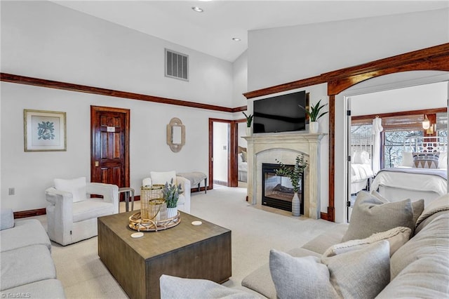 living room with high vaulted ceiling, a fireplace, and light colored carpet