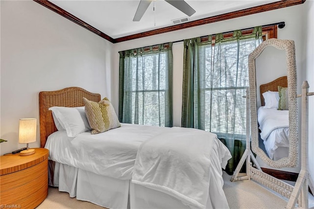 carpeted bedroom with ornamental molding and ceiling fan