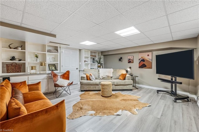 living room with built in shelves and light hardwood / wood-style flooring