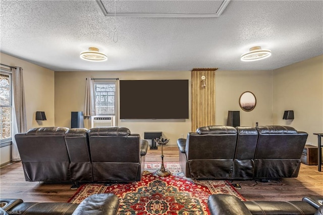 home theater room featuring wood-type flooring, plenty of natural light, and a textured ceiling
