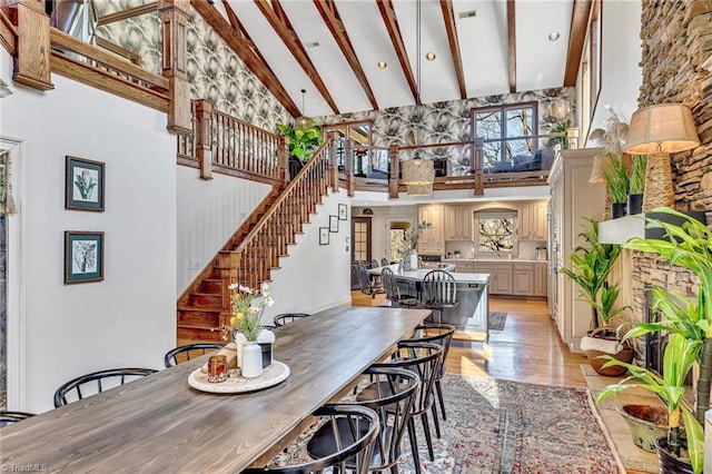 dining room with beamed ceiling, high vaulted ceiling, and light wood-type flooring