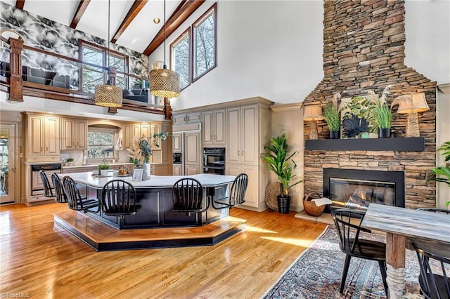 interior space with lofted ceiling with beams, a fireplace, and light hardwood / wood-style flooring