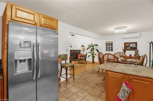 206 Westwood Dr, Kernersville, NC 27284 - kitchen featuring light stone counters, a wall mounted AC, a fireplace, and stainless steel refrigerator with ice dispenser