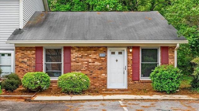 view of front facade with brick siding and a shingled roof