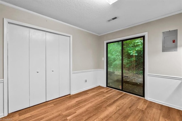 unfurnished bedroom featuring electric panel, crown molding, visible vents, light wood-style flooring, and a textured ceiling