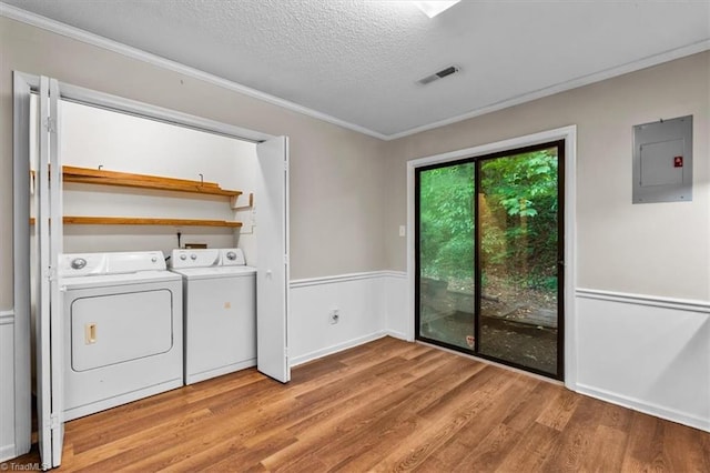 laundry area featuring washing machine and dryer, electric panel, laundry area, light wood-type flooring, and a textured ceiling