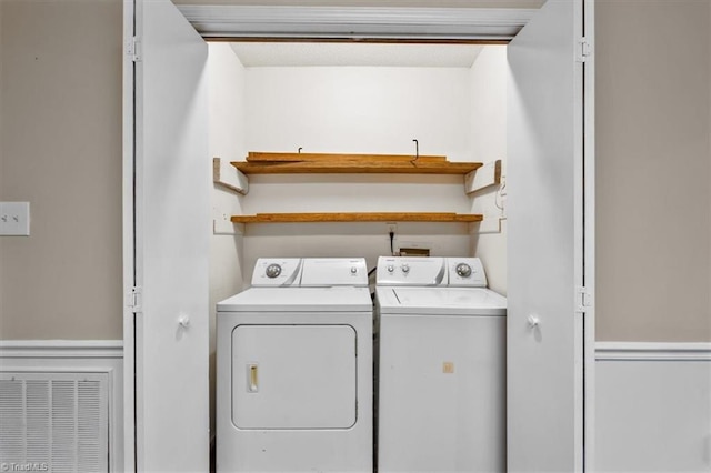 washroom featuring visible vents, washing machine and clothes dryer, and laundry area
