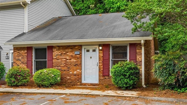 view of front of home featuring brick siding and a shingled roof